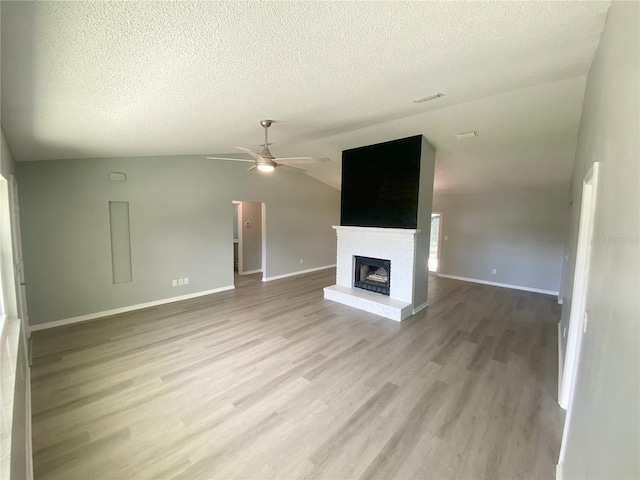 unfurnished living room with lofted ceiling, hardwood / wood-style floors, ceiling fan, and a textured ceiling