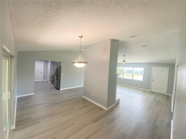 spare room with wood-type flooring, a textured ceiling, and vaulted ceiling