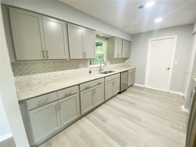 kitchen featuring light stone countertops, dishwasher, backsplash, light hardwood / wood-style floors, and sink