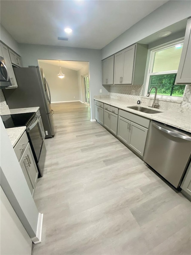 kitchen featuring stainless steel appliances, light hardwood / wood-style floors, tasteful backsplash, and sink