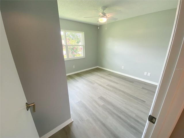 spare room with ceiling fan, light hardwood / wood-style floors, and a textured ceiling