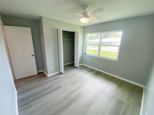 unfurnished bedroom featuring a closet, a textured ceiling, ceiling fan, and light hardwood / wood-style floors