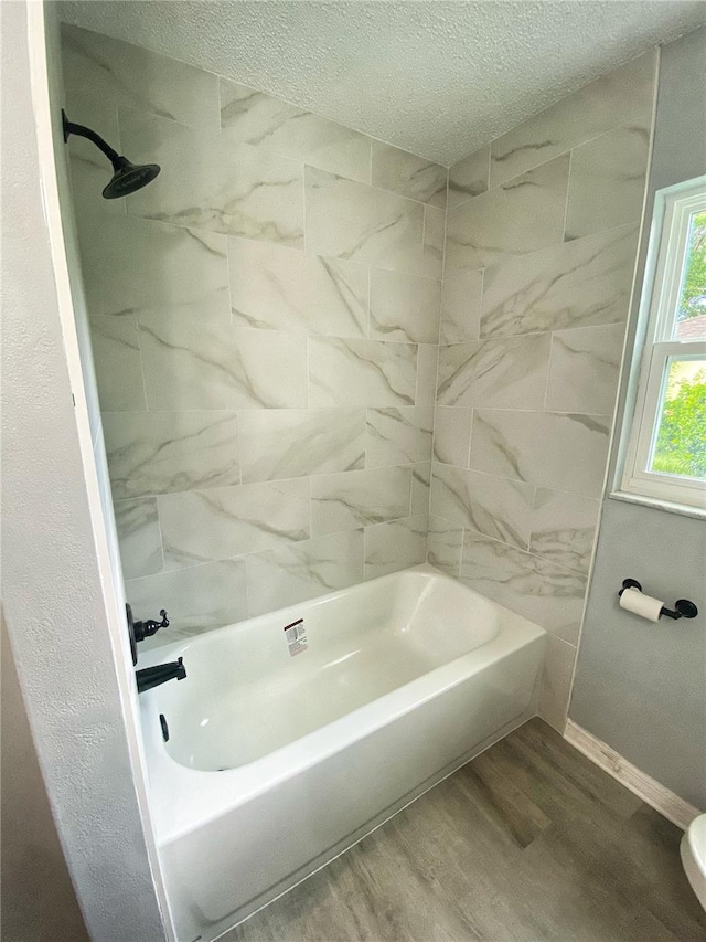 bathroom with tiled shower / bath, a textured ceiling, and hardwood / wood-style floors