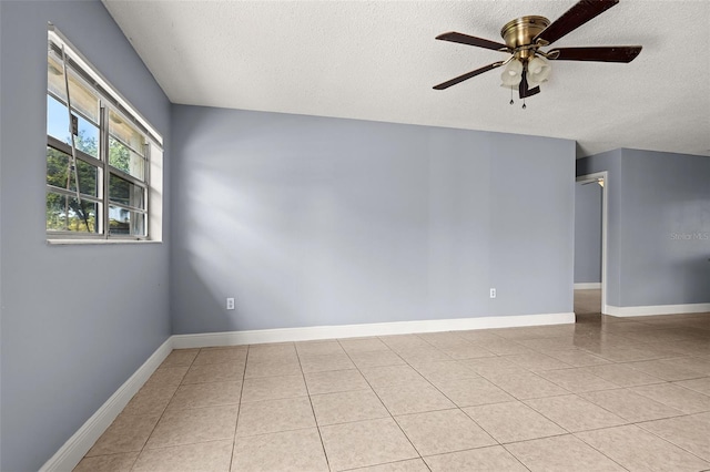 empty room featuring ceiling fan, light tile patterned floors, and a textured ceiling