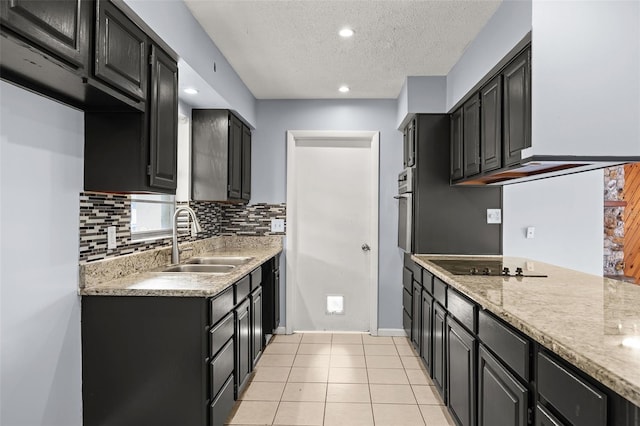 kitchen with black electric stovetop, sink, light tile patterned floors, a textured ceiling, and light stone counters