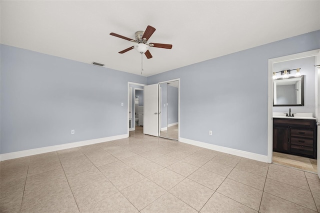 unfurnished bedroom featuring ensuite bathroom, ceiling fan, sink, a closet, and light tile patterned flooring