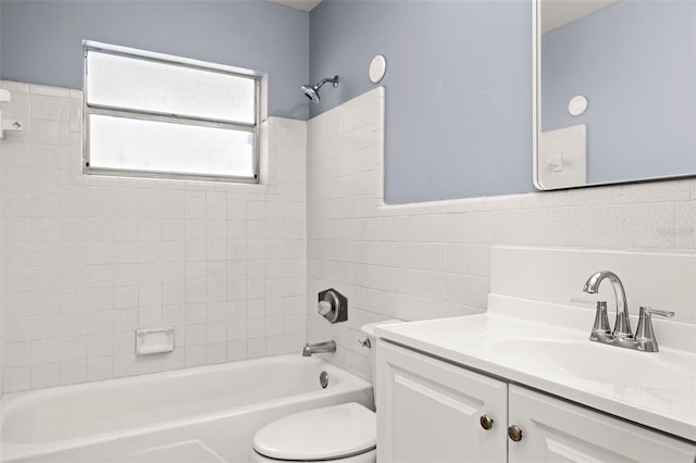 full bathroom featuring tiled shower / bath, vanity, tile walls, and toilet