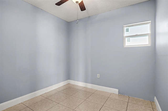 spare room featuring ceiling fan, light tile patterned flooring, and a textured ceiling