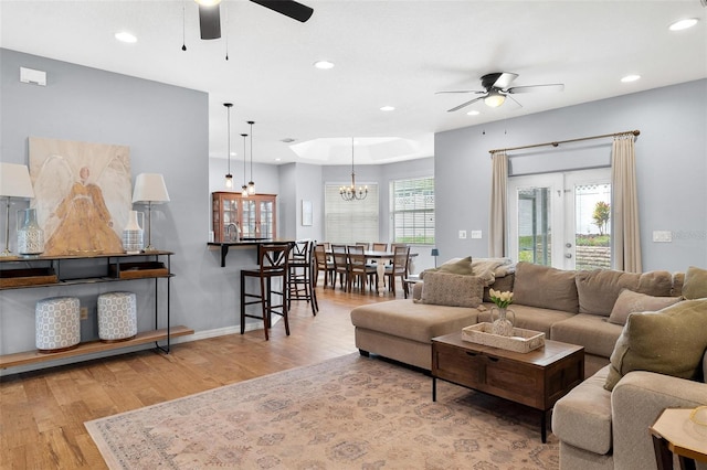 living room featuring plenty of natural light, ceiling fan with notable chandelier, and light hardwood / wood-style flooring