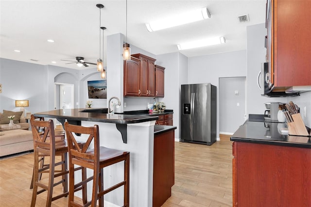 kitchen featuring ceiling fan, stainless steel appliances, kitchen peninsula, light hardwood / wood-style floors, and a kitchen bar