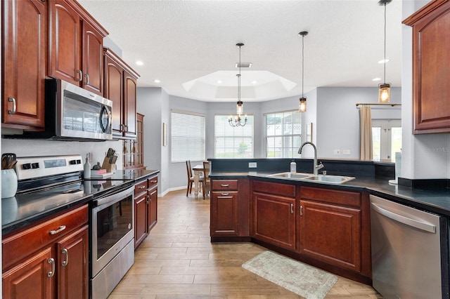 kitchen featuring sink, hanging light fixtures, a notable chandelier, appliances with stainless steel finishes, and light wood-type flooring