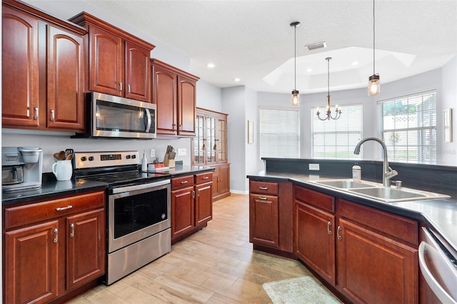 kitchen featuring sink, hanging light fixtures, a notable chandelier, light hardwood / wood-style floors, and appliances with stainless steel finishes