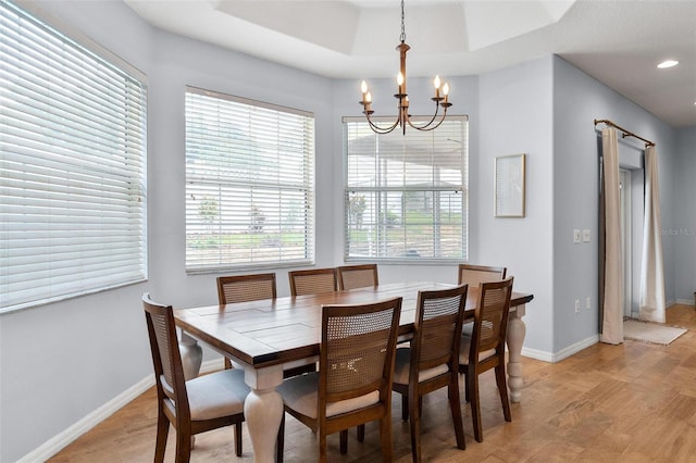 dining room featuring a raised ceiling, light wood-type flooring, and an inviting chandelier