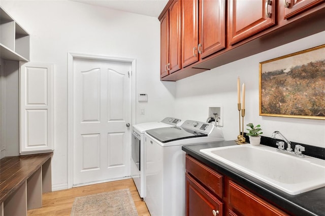 laundry area featuring washer and clothes dryer, light hardwood / wood-style flooring, cabinets, and sink