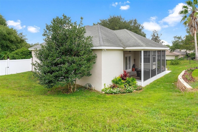 rear view of house with a lawn and a sunroom