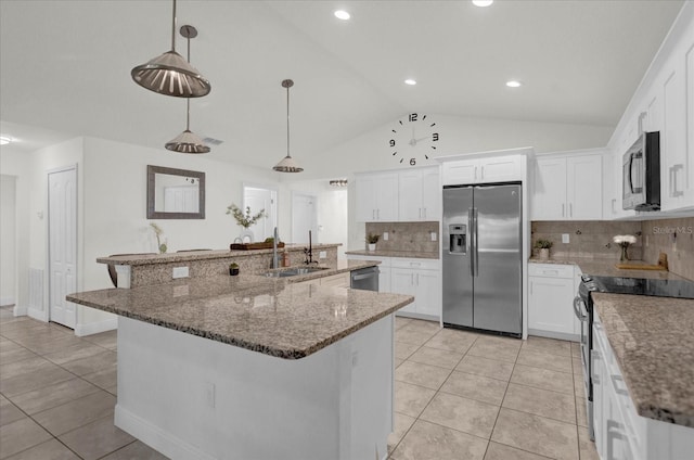 kitchen with white cabinetry, an island with sink, pendant lighting, lofted ceiling, and appliances with stainless steel finishes