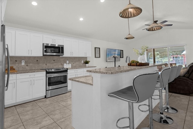 kitchen with white cabinetry, hanging light fixtures, vaulted ceiling, and appliances with stainless steel finishes