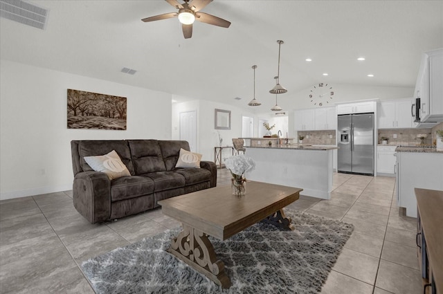 living room featuring ceiling fan, light tile patterned floors, and vaulted ceiling