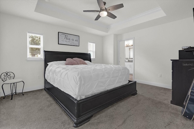 bedroom with carpet, ceiling fan, connected bathroom, and a tray ceiling