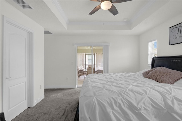 carpeted bedroom with a raised ceiling, multiple windows, ceiling fan, and ornamental molding