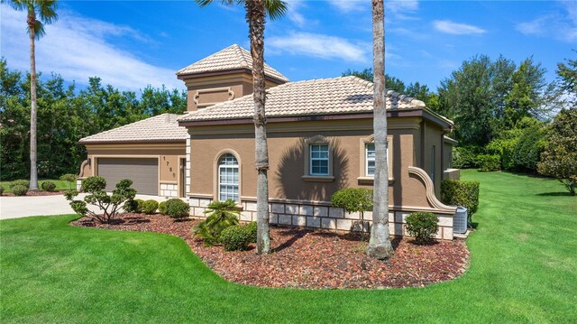 mediterranean / spanish home featuring a garage and a front lawn