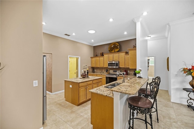 kitchen with kitchen peninsula, light stone countertops, a breakfast bar, stainless steel appliances, and sink