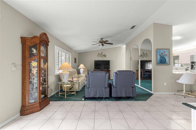 tiled living room with a textured ceiling, ceiling fan, and lofted ceiling