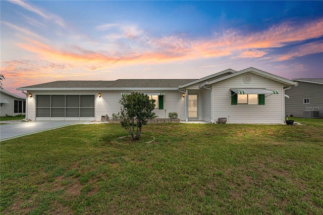 ranch-style home with cooling unit, a lawn, and a garage