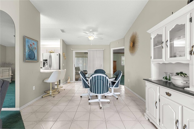 tiled dining area with a textured ceiling and ceiling fan