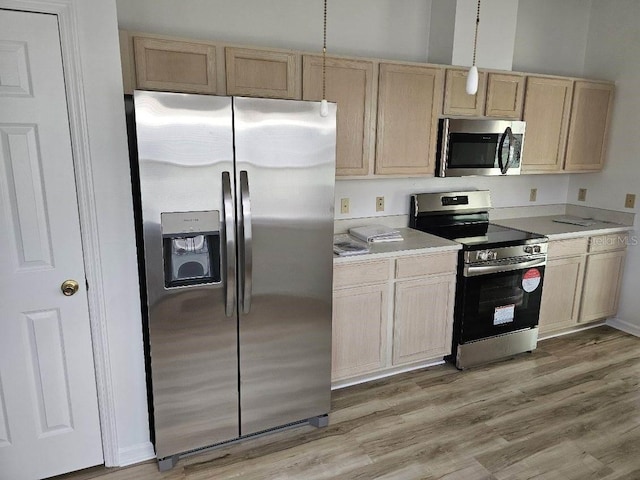 kitchen featuring decorative light fixtures, appliances with stainless steel finishes, light brown cabinets, and hardwood / wood-style floors