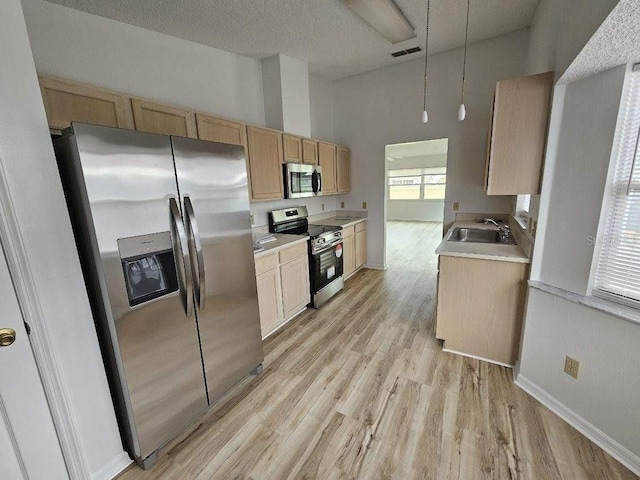 kitchen featuring light hardwood / wood-style floors, appliances with stainless steel finishes, a high ceiling, light brown cabinetry, and sink