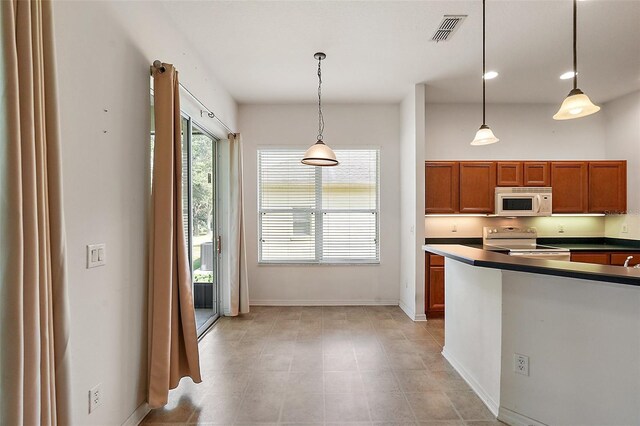 kitchen with white appliances, light tile patterned floors, and hanging light fixtures