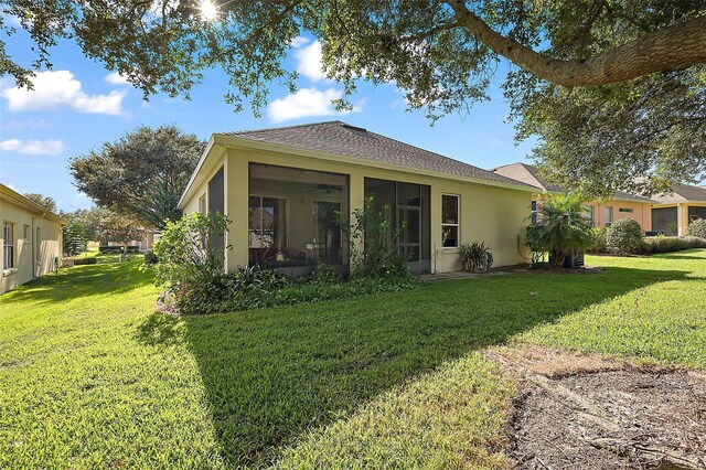 rear view of property with ceiling fan and a yard