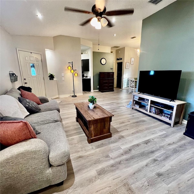 living room featuring ceiling fan, lofted ceiling, and light wood-type flooring