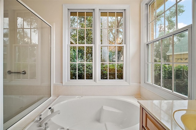 bathroom with vanity, a healthy amount of sunlight, and a bath