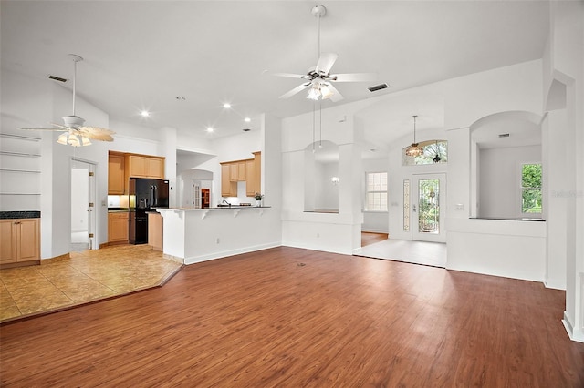 unfurnished living room with light wood-type flooring, high vaulted ceiling, and ceiling fan