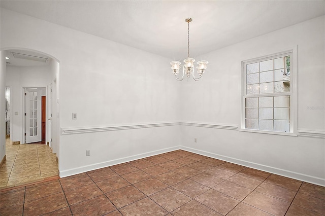 tiled spare room with a chandelier