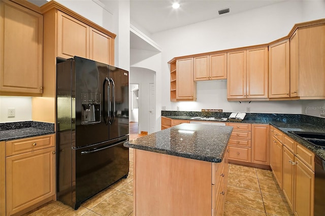 kitchen with light brown cabinetry, a center island, light tile patterned floors, and black appliances