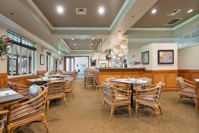 dining area featuring a raised ceiling, light colored carpet, and crown molding