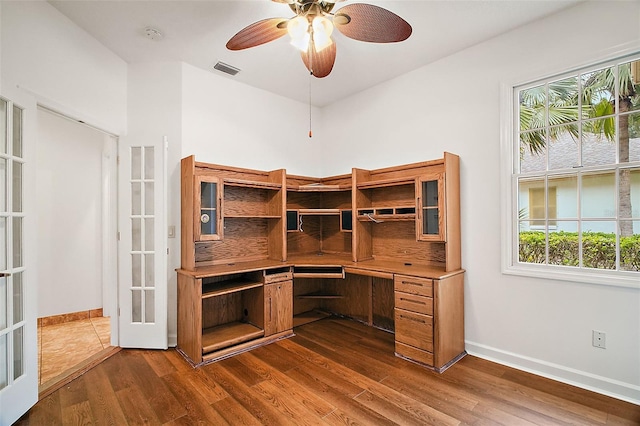 unfurnished office with french doors, built in desk, dark hardwood / wood-style floors, and ceiling fan