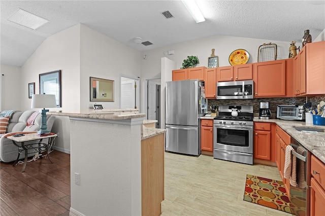 kitchen with lofted ceiling, light wood finished floors, visible vents, and appliances with stainless steel finishes