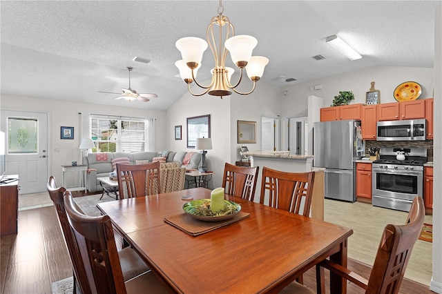 dining area with lofted ceiling, light hardwood / wood-style flooring, ceiling fan with notable chandelier, and a textured ceiling