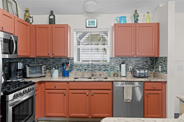 kitchen featuring appliances with stainless steel finishes, light stone counters, backsplash, and sink