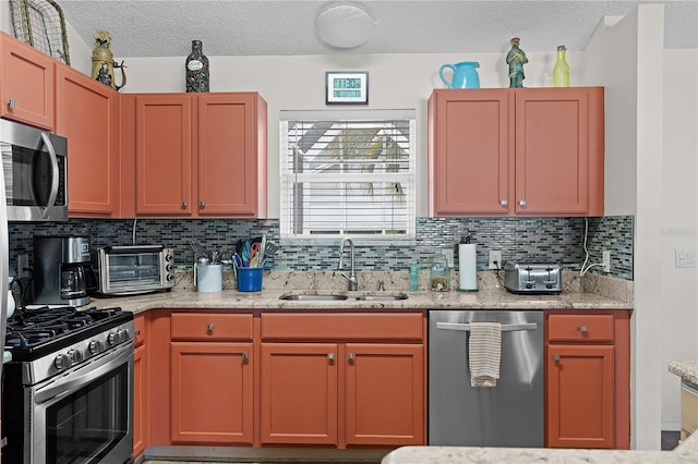 kitchen featuring a toaster, decorative backsplash, light stone countertops, stainless steel appliances, and a sink