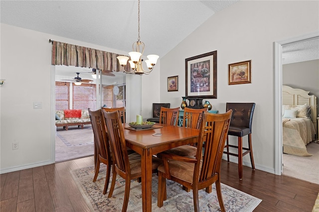 dining space featuring dark wood-type flooring, ceiling fan with notable chandelier, lofted ceiling, and a textured ceiling