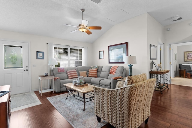 living room with lofted ceiling, dark wood-type flooring, ceiling fan, and a textured ceiling