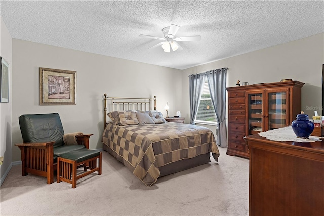 bedroom featuring ceiling fan, light carpet, and a textured ceiling