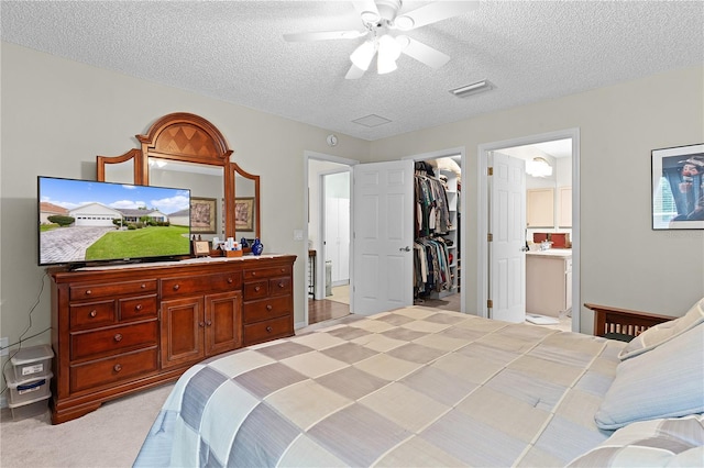 carpeted bedroom featuring a textured ceiling, a spacious closet, a closet, connected bathroom, and ceiling fan