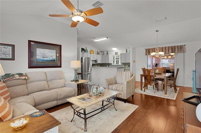 17913 SE 88th Cascade Ct, The Villages, FL 32162 - living room featuring ceiling fan with notable chandelier, dark wood-style floors, vaulted ceiling, and visible vents