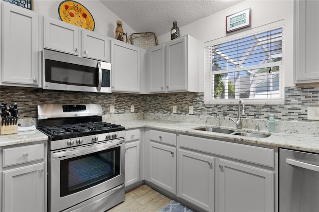 17913 SE 88th Cascade Ct, The Villages, FL 32162 - kitchen featuring decorative backsplash, a textured ceiling, a sink, light wood-style flooring, and appliances with stainless steel finishes